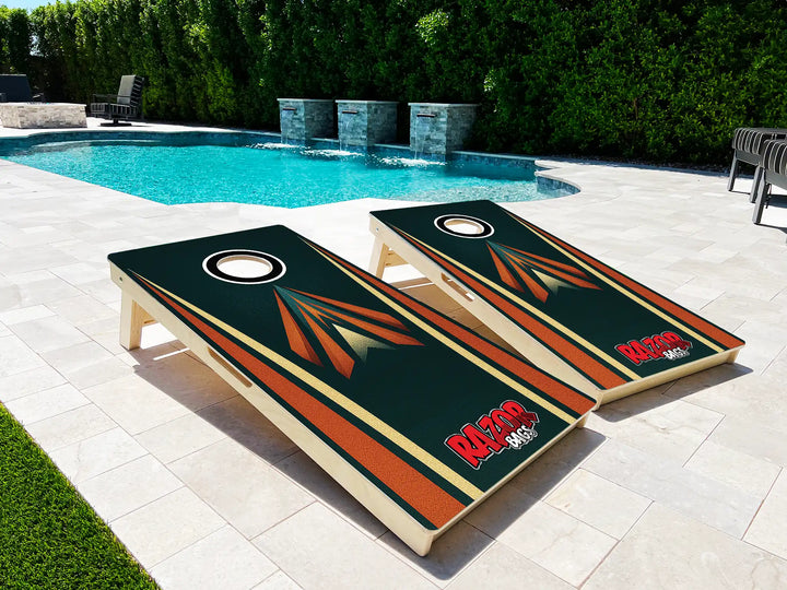 Two cornhole boards with a logo on a patio near a pool