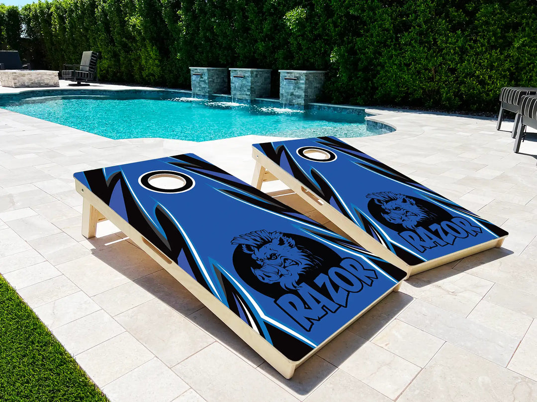 Two cornhole boards with a Pig design and 'RAZOR' text on a patio near a pool.