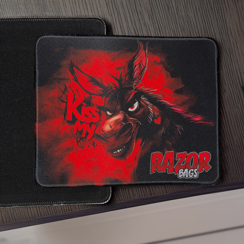Mouse pad with a graphic design of a demon-like creature and 'Kiss My Razor Bags' text on a dark surface.