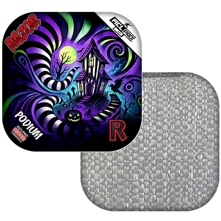 Colorful cornhole bag with a haunted house design and Razor branding, next to a gray textured square.